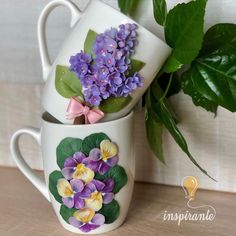 three mugs with flowers painted on them are sitting next to a potted plant