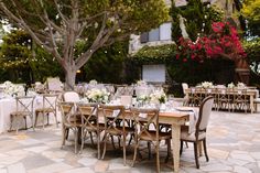 tables and chairs are set up for an outdoor wedding reception with white linens on them