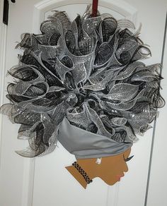 a woman's head is adorned with black mesh and silver sequins as she stands in front of a white door