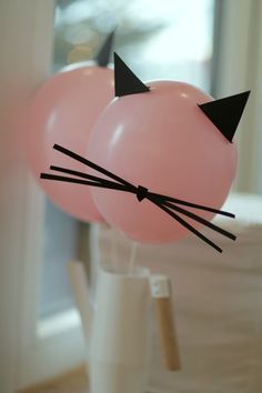 two pink balloons with black cat ears on them