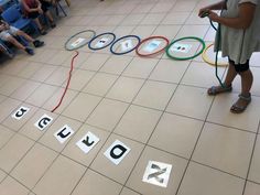 a group of children sitting on chairs in front of a floor with letters spelling out