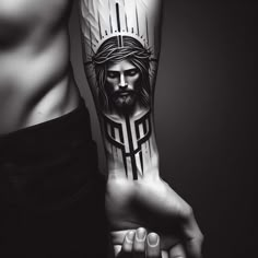 a man's arm with a jesus tattoo on it and his hand holding the cross