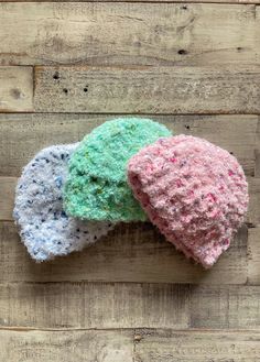 three crocheted hats sitting on top of a wooden floor