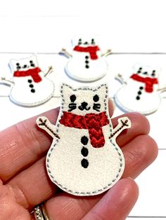 a hand holding a small white snowman with red scarf