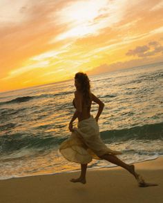 a woman running on the beach at sunset