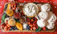 a platter filled with fruit and dips on top of a red table cloth