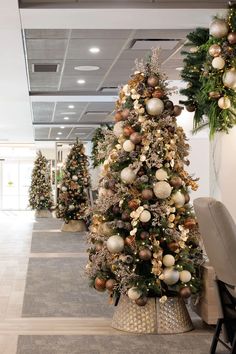 a christmas tree in an office decorated with gold and silver balls, greenery and ornaments