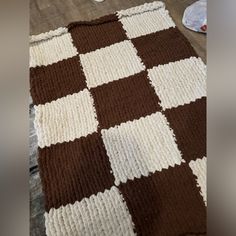 a brown and white blanket sitting on top of a floor next to a pile of shoes