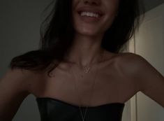 a woman wearing a strapless black dress smiling at the camera