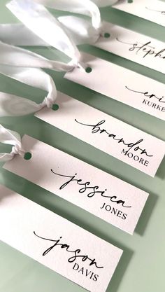 some white tags with black writing on them are tied together and ready to be used as place cards