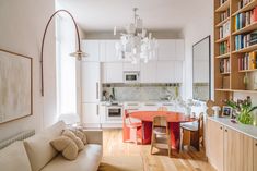 a living room filled with furniture next to a kitchen and dining room table surrounded by bookshelves