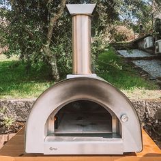 an outdoor pizza oven sitting on top of a wooden table