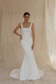 a woman in a white wedding dress posing for the camera with her hands on her hips