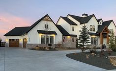 a large white house with lots of windows and lights on it's front porch