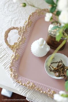 there is a tray with rings on it and flowers in the vase next to it