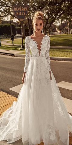 a woman in a white wedding dress standing on the street with her back to the camera