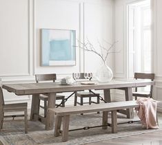 a dining room table with two benches and a vase on the table next to it