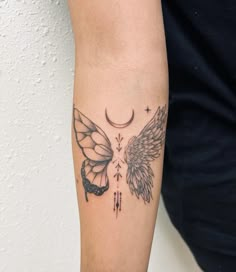 a woman's arm with a tattoo on it that has two wings and a crescent