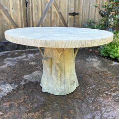 a stone table sitting on top of a rock covered ground next to a wooden fence