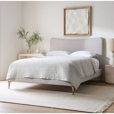 a bed with white sheets and pillows in a room next to a rug on the floor