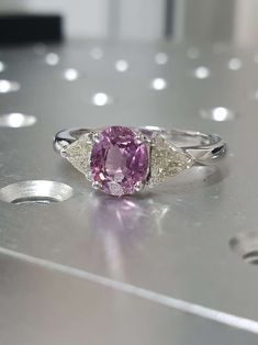 a pink and white diamond ring sitting on top of a table