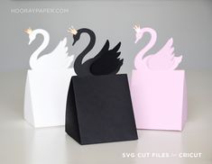 three paper swans sitting on top of each other in front of a white and pink box