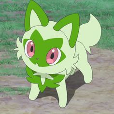 a green and white cat walking on top of a dirt road next to grass covered ground