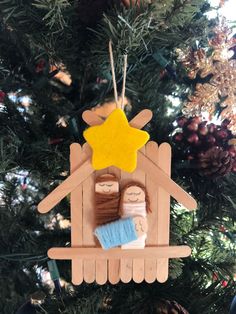 a wooden ornament with a nativity scene hanging on a christmas tree branch