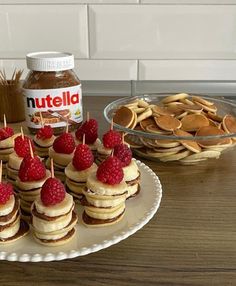 some pancakes and raspberries are arranged on a plate with peanut butter in the background