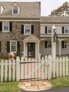 a white picket fence in front of a stone house