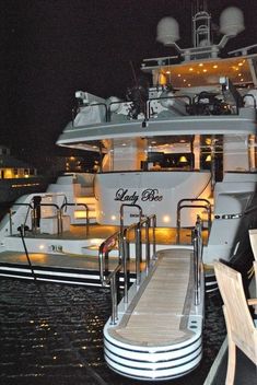 a large white boat docked next to a dock at night with people sitting on chairs