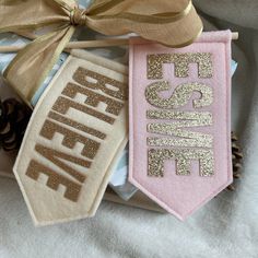 three pieces of fabric with the words peace on them, tied together and sitting next to pine cones