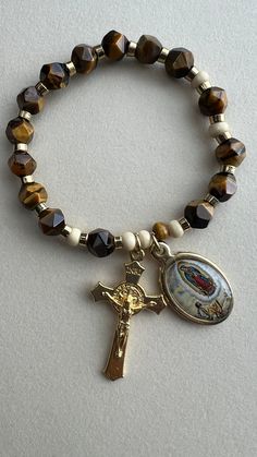 Handmade Rosary Bracelet with Tiger Eye Faceted 8mm, Beige and brown wooden beads with gold  4" spacers were also used, a Crystal Strong & Stretchy String was also used, the charms are from our Lady of Guadalupe and a crucifix both in gold, made in Italy. The total measurement of the bracelet is 7 inches or 17.8 cm. Beautiful instrument of prayer or to give as a gift on any special occasion. Spiritual Rosary Bracelet With Miraculous Medal, Adjustable Spiritual Rosary With Miraculous Medal, Adjustable Crucifix Spiritual Bracelet, Spiritual Beaded Bracelets With Miraculous Medal, Spiritual Bracelets With Miraculous Medal As Gift, Spiritual Our Lady Of Guadalupe Bracelets As Gifts, Adjustable Beaded Rosary Bracelet With Crucifix, Adjustable Spiritual Bracelets With Miraculous Medal, Spiritual Beaded Rosary Bracelet For Blessing