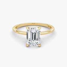 a yellow gold ring with an emerald cut diamond