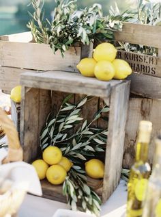 some lemons are sitting in crates on a table with other food and wine bottles