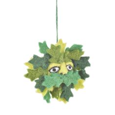 an ornament with leaves and eyes hanging from a string on a white background