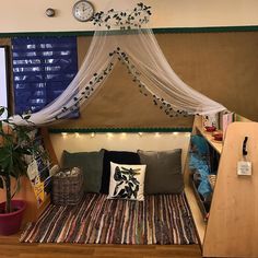 a bed with a canopy over it and some pillows on top of it in front of a window