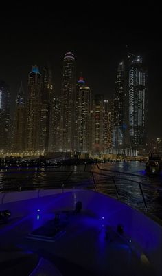 the city skyline is lit up at night as seen from a boat in the water