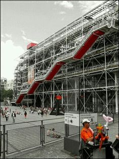 people are sitting in front of a large building with scaffolding on the side