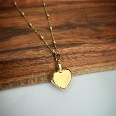 a gold heart necklace on a wooden surface