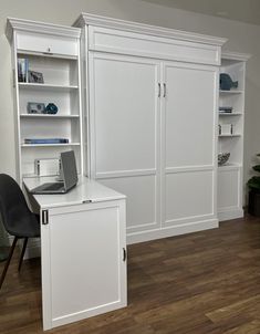 a white desk with a laptop on top of it next to a bookcase and cabinets