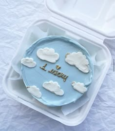 a blue cake with white clouds and the words i love you written on it in gold letters