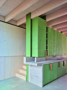 an empty kitchen with green cabinets and white counter tops in a large room that has unfinished walls