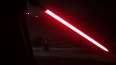 a person standing in the dark with a red light saber on their arm and a black background