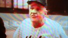 an old man in a baseball uniform is on the television screen with his eyes closed