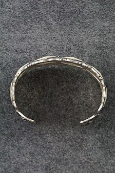 This sterling silver bracelet was made by Navajo silversmith Leander Tahe. The inside is signed L. Tahe and stamped sterling.Size: 6" (will fit up to a 7 1/4" wrist)Gap: 1 1/4"Width: 1 1/2"Free shipping on all orders! We ship with USPS and always include tracking. All orders ship within a day of payment.Returns are accepted up to 30 days after you receive your order. Just send us a message. Our shop offers cash back or store credit. The item must be returned in new condition. Artisan Sterling Silver Bracelet With Oxidized Finish, Silver Southwestern Style Bracelet With Oyster Clasp, Southwestern Silver Cuff Bracelet With Oyster Detail, Sterling Silver Oxidized Bangle Bracelet, Silver Southwestern Style Oyster Bracelet, Southwestern Style Silver Oyster Bracelet, Artisan Sterling Silver Bracelet With Oyster Detail, Artisan Sterling Silver Oyster Bracelet, Sterling Silver Bracelet