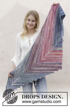 a woman holding up a multicolored shawl