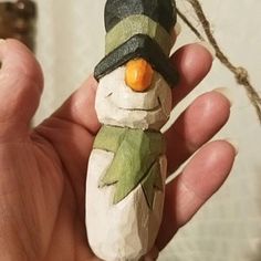 a hand holding a small wooden snowman ornament