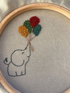 an elephant with flowers in it's trunk is shown on the embroidery hoop that has been stitched onto