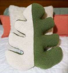 a crocheted stuffed animal sitting on top of a bed next to a pillow